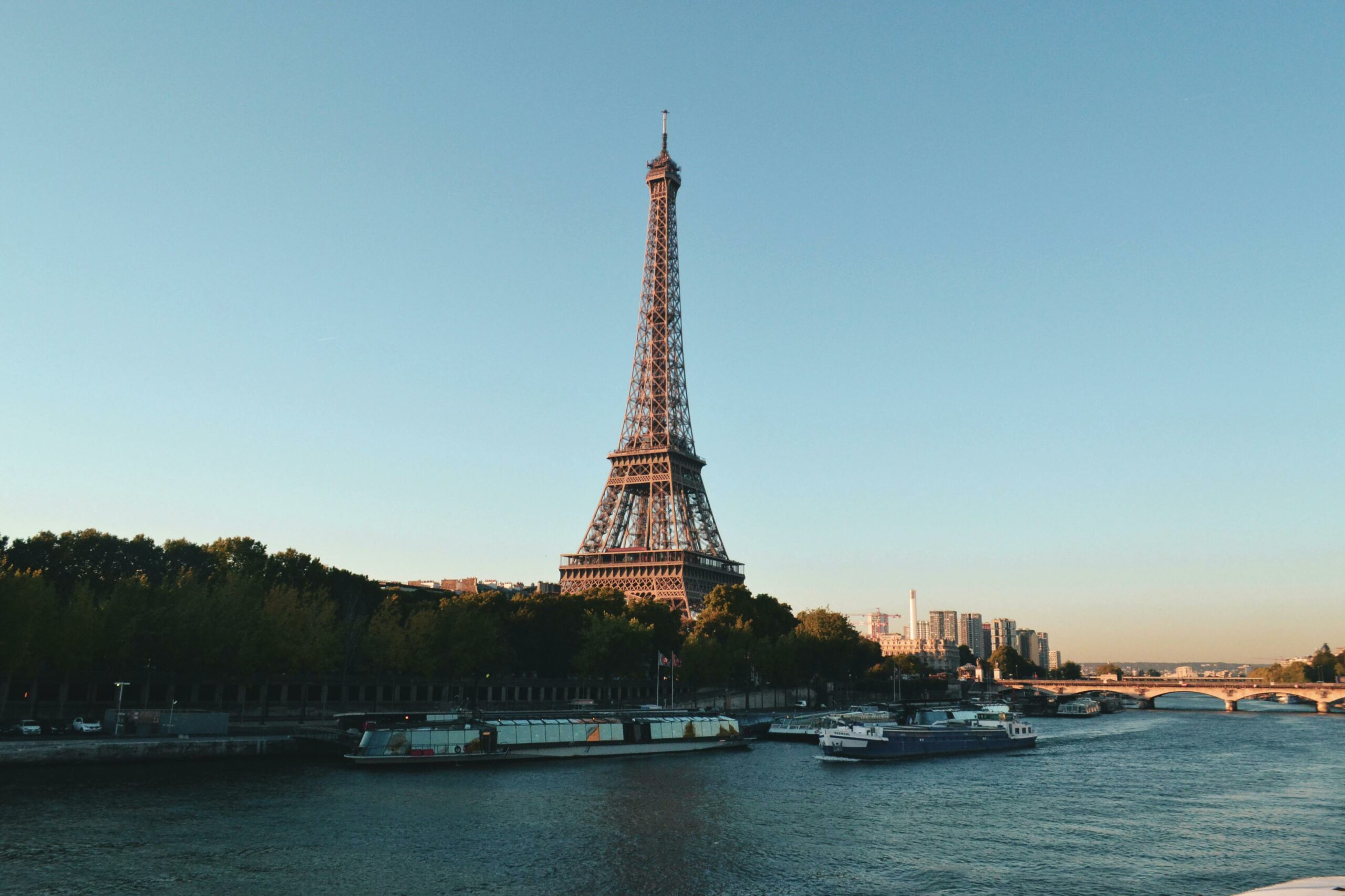 Scenic view of the Eiffel Tower and Seine River at sunset, showcasing iconic Parisian architecture.