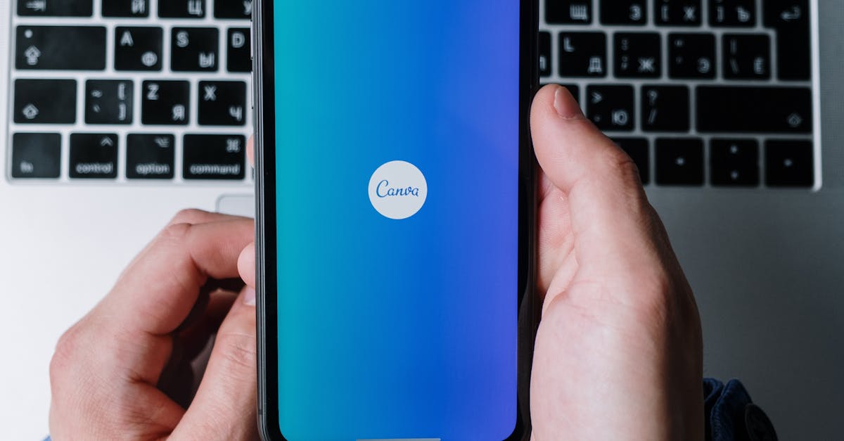 Hands holding smartphone with app open, placed over laptop keyboard, technology concept.